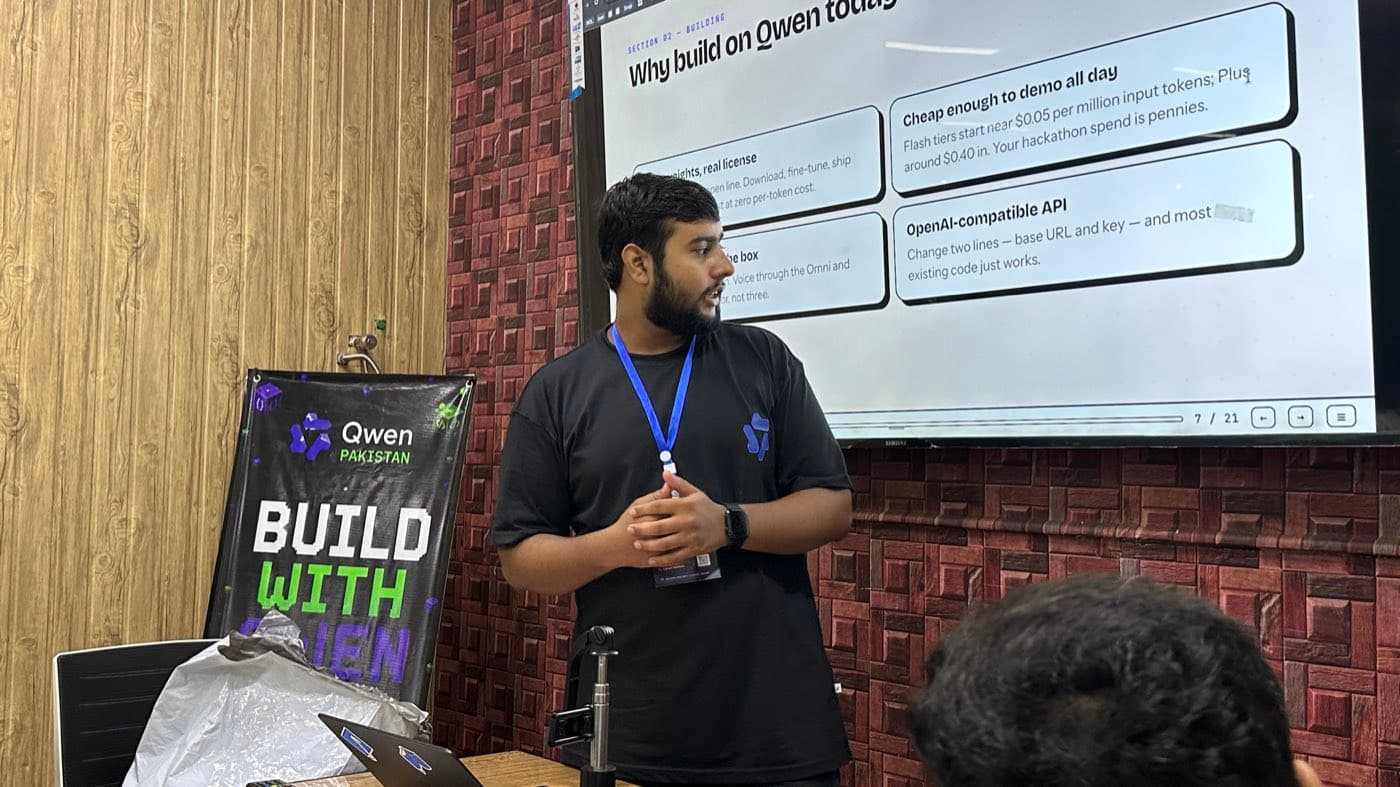 Junaid speaking in front of a slide titled Why build on Qwen today, next to a Build With Qwen banner